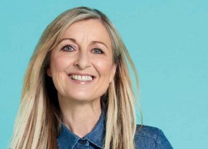 Fiona Phillips smiling at the camera on blue background