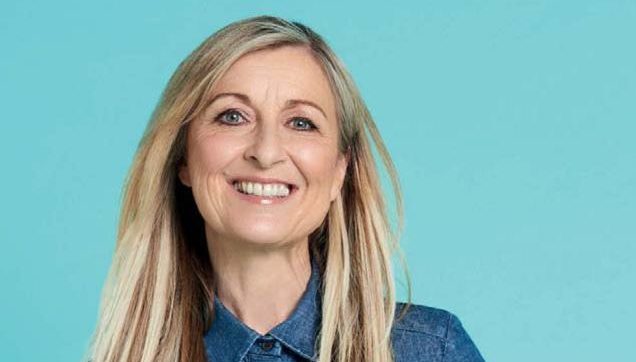 Fiona Phillips smiling at the camera on blue background