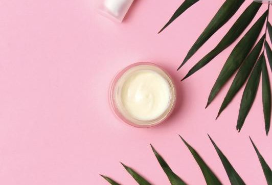 A pot of face cream on a pink background