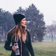 Woman in fitness gear and woolly hat walking across a field