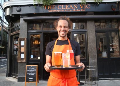 Man holding a tray of non-alcoholic drinks outside pub