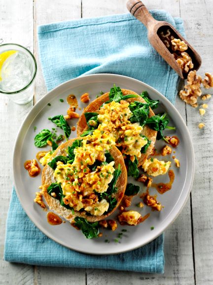 A bagel topped with scrambled egg, walnuts and paprika