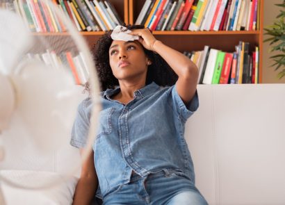 Girl wiping her sweaty brow in front of fan