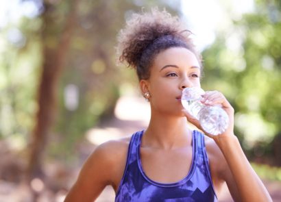 Woman drinking from a bottle of water in the park