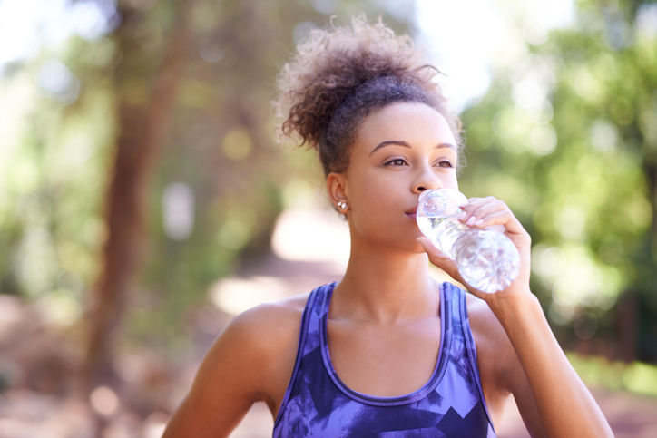 Woman drinking from a bottle of water in the park