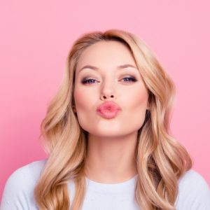 Young woman pouting at the camera in front of pink background