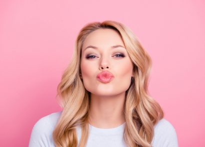 Young woman pouting at the camera in front of pink background