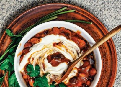 Vegan chilli con carne in a white bowl with wooden spoon