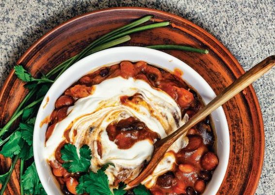 Vegan chilli con carne in a white bowl with wooden spoon