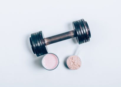 Whey protein drink in a glass next to a dumbbell weighr