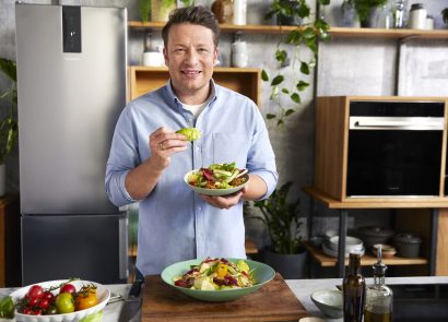 Jamie Oliver holding a freshly made dish that looks too delicious to eat
