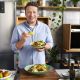 Jamie Oliver holding a freshly made dish that looks too delicious to eat