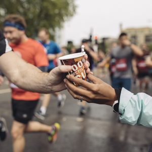 Runner being handed a cardboard cup of water on race