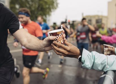 Runner being handed a cardboard cup of water on race