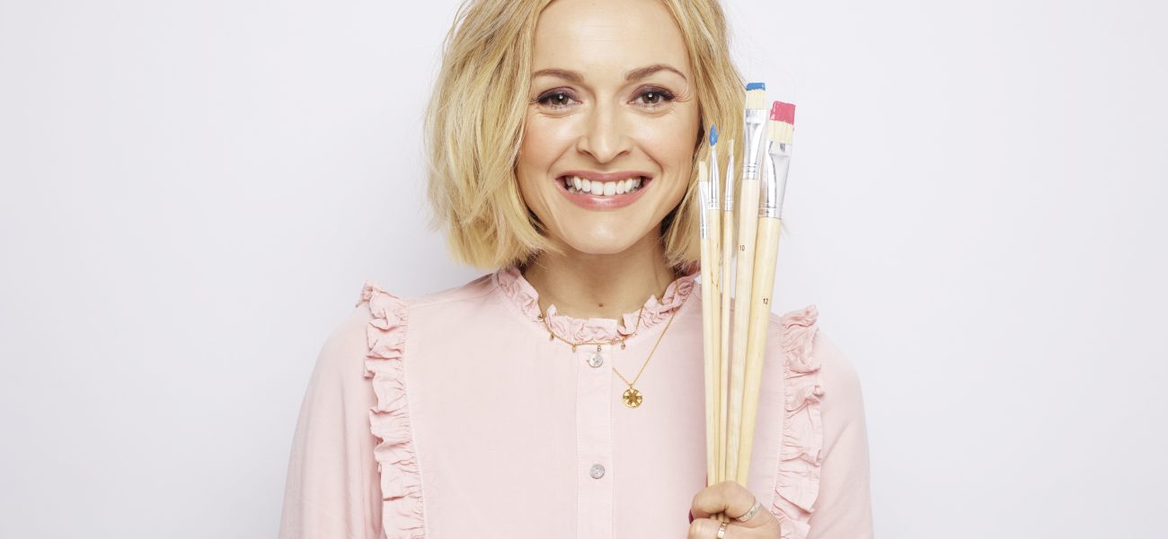 Fearne Cotton smiling and holding a set of paint brushes