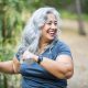 Happy older woman smiling and using weights outdoors