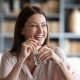 Woman smiling, holding pill and glass of water, after beating bloating