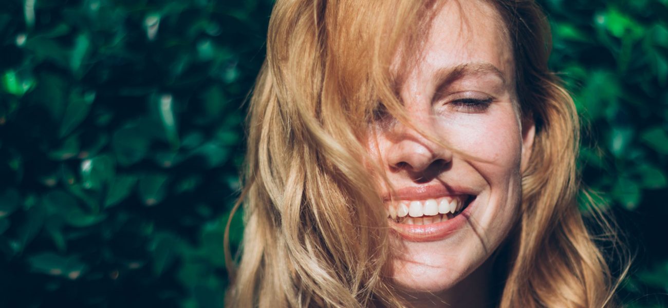 Woman smiling in the sunshine, enjoying vitamin D