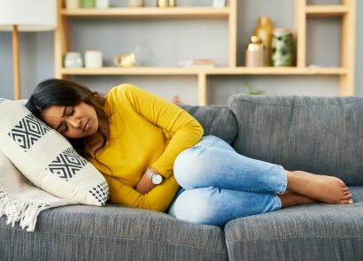 Shot of a young woman suffering from stomach cramps at home