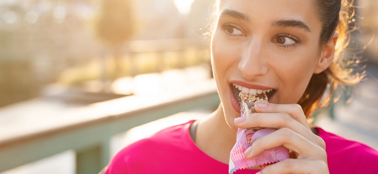 woman outside eating protein bar healthy snack