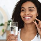 woman taking supplement with water