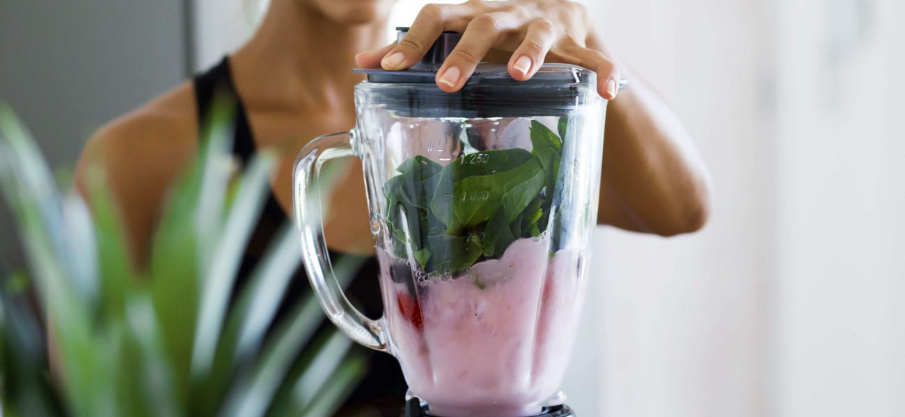 woman making a healthy smoothie in a blender