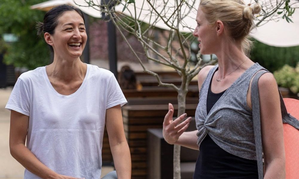 two girlfriends going to exercise together with their mats