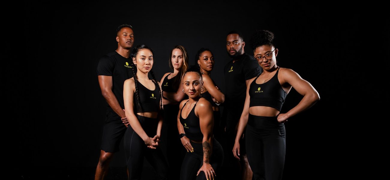 diverse group of personal trainers posing on a black background