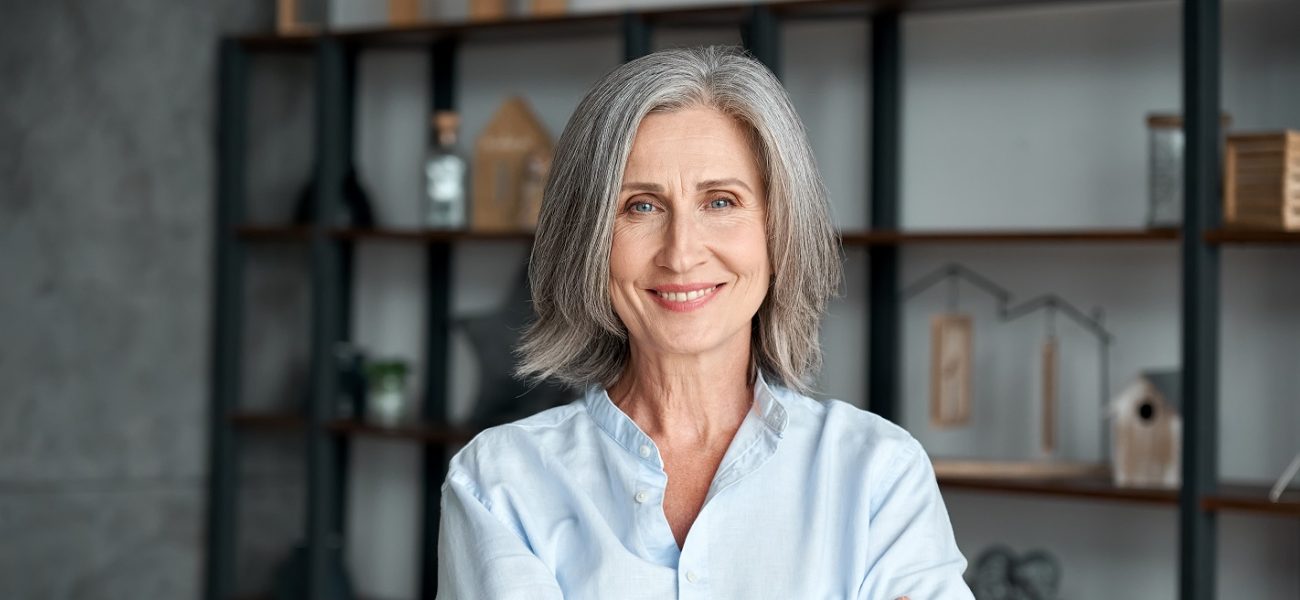 mature woman smiling at the camera with her arms crossed