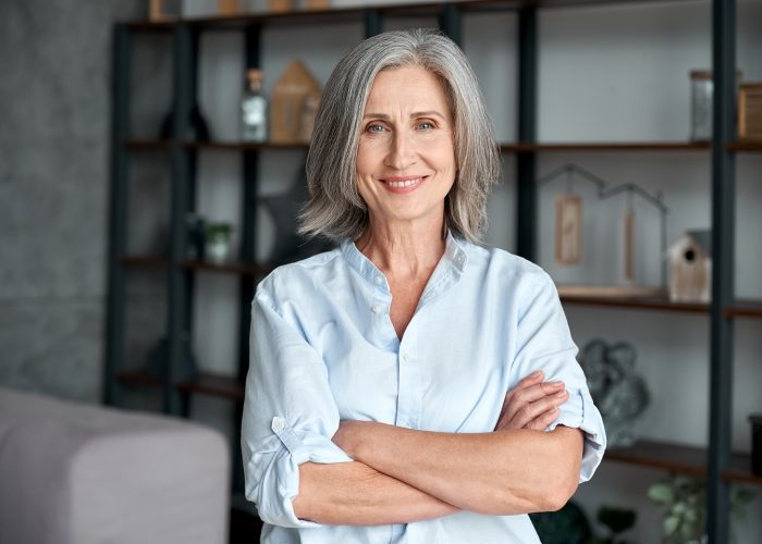 mature woman smiling at the camera with her arms crossed