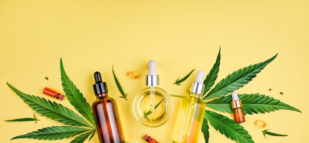 bottles of CBD oils and cannabis plants on a bright yellow background