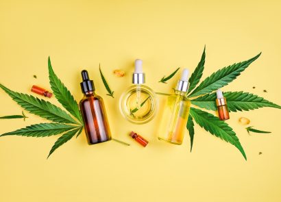 bottles of CBD oils and cannabis plants on a bright yellow background