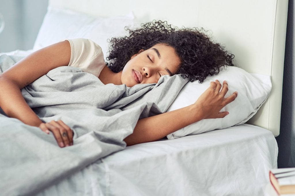 Young woman of colour sleeping peacefully in her bed