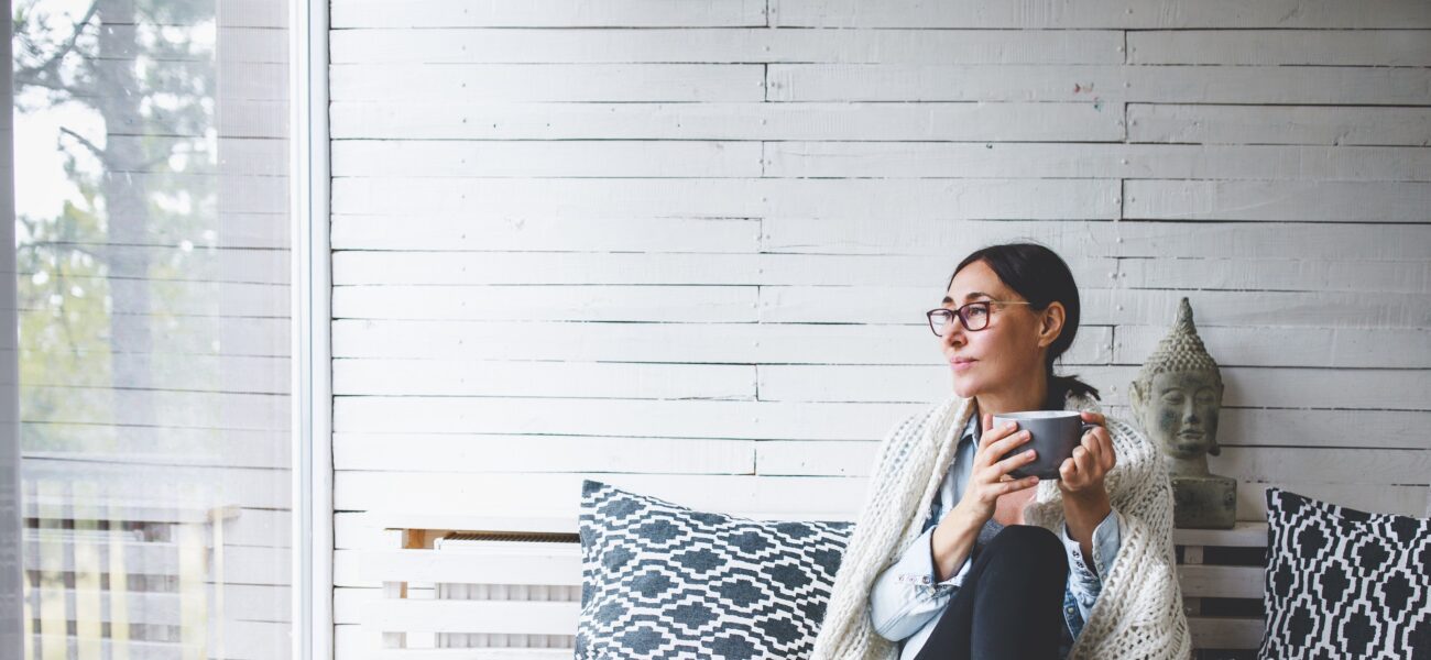 Woman sitting comfortable drinking tea and looking through window