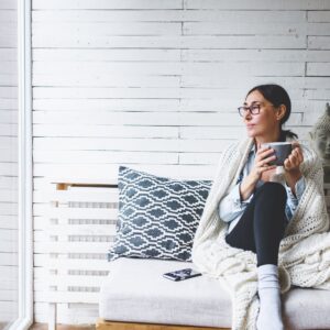 Woman sitting comfortable drinking tea and looking through window