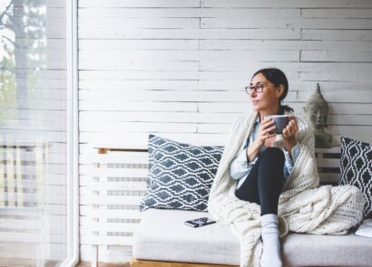 Woman sitting comfortable drinking tea and looking through window