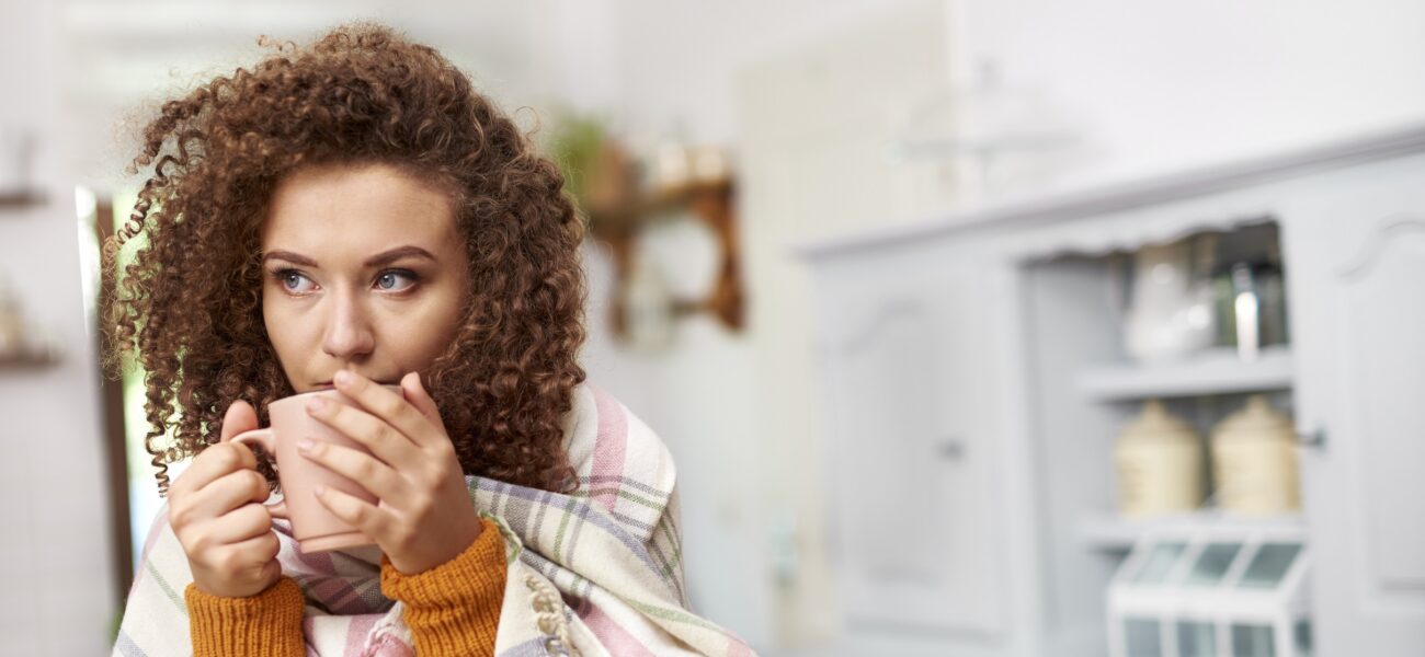 woman wrapped in scarf drinking tea in the kitchen