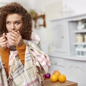 woman wrapped in scarf drinking tea in the kitchen