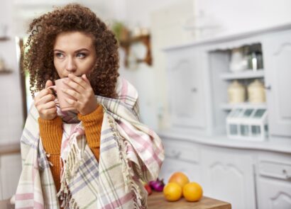 woman wrapped in scarf drinking tea in the kitchen