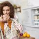 woman wrapped in scarf drinking tea in the kitchen