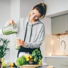 woman in loungewear making a healthy green smoothie in a modern kitchen