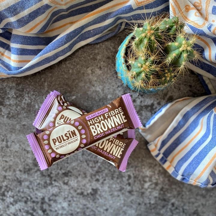 Pulsin's plant based brownie in packaging with cactus and striped tea towel