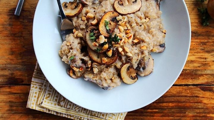 creamy mushroom risotto in a white bowl on a wooden table