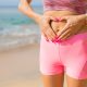 Fit woman showing hands heart sign on her stomach