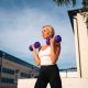 Beautiful blonde middle age woman doing weights exercises with dumbbells outdoors