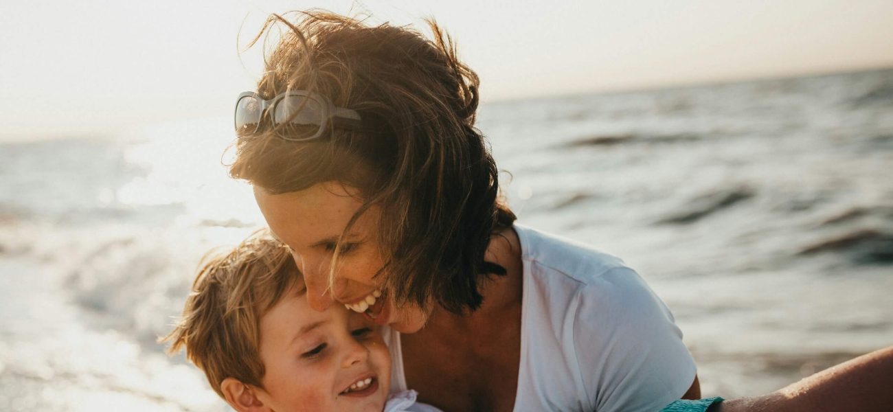 A happy mother carrying her son on the beach
