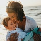 A happy mother carrying her son on the beach