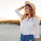 A woman wearing a hat standing beside a river