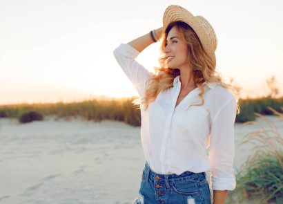 A woman wearing a hat standing beside a river