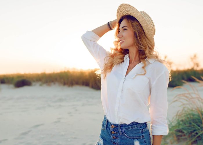 A woman wearing a hat standing beside a river